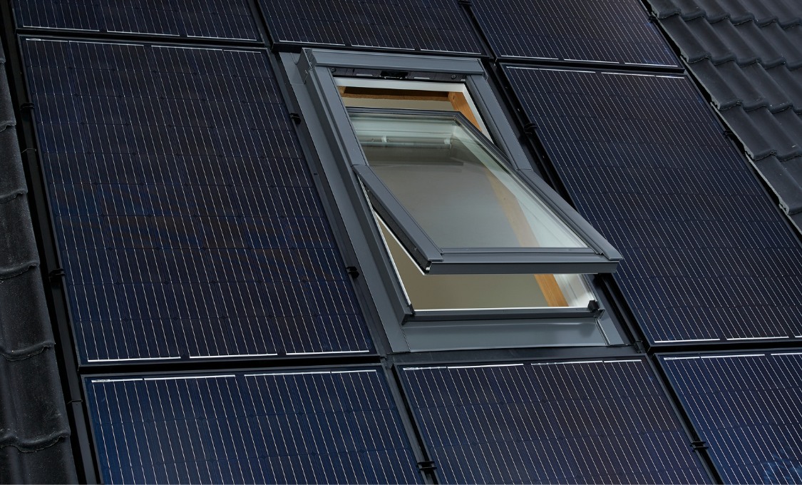 Dachfenster eingebaut zwischen Solarpanels auf einem Dach. Das Fenster ist geöffnet und zeigt einen Blick ins Innere des Gebäudes, während die Solarpanels den gesamten Dachbereich bedecken.