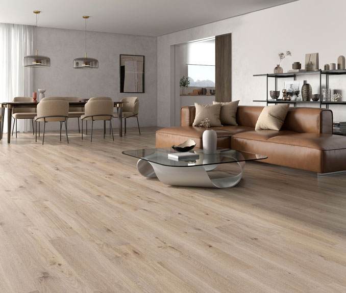 Modernes Wohnzimmer mit einem braunen Ledersofa, einem Glastisch und einem Esstisch mit Stühlen. Der Raum ist mit hellem Holzfußboden ausgestattet und von natürlichem Licht durch große Fenster erleuchtet.